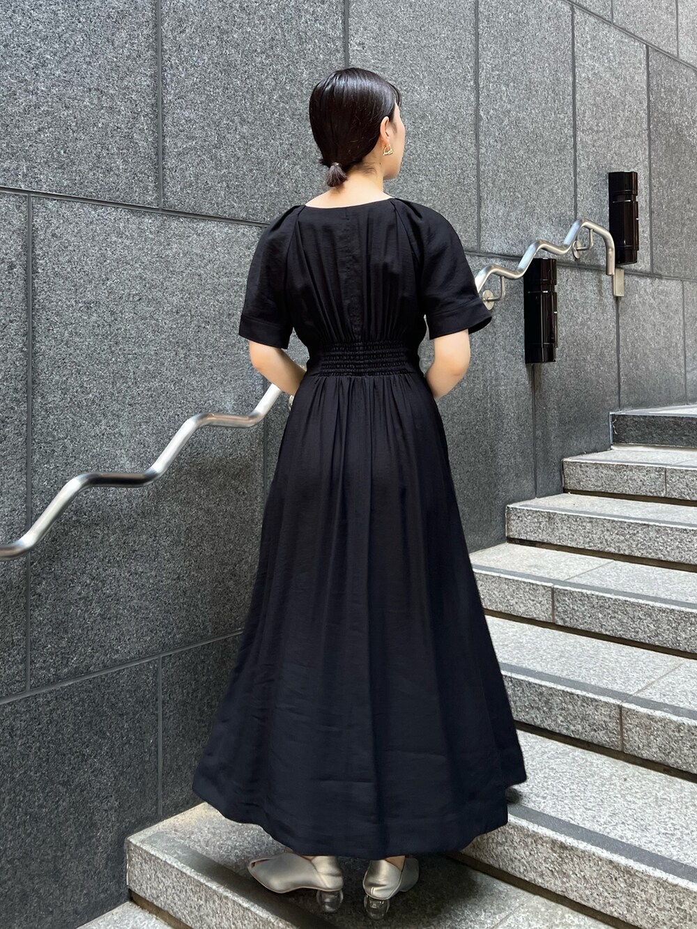 ブラック系のワンピース、ブラック系のショルダーバッグ、シルバー系のパンプスを着用したレディースの夏コーディネートの3枚目の写真