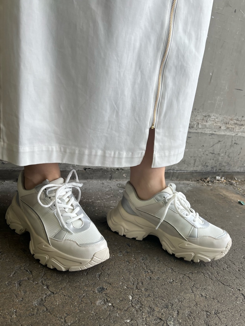 ホワイト系のジャンパースカート、ベージュ系のハンドバッグ、ホワイト系のTシャツ/カットソーを着用したレディースの春コーディネートの5枚目の写真