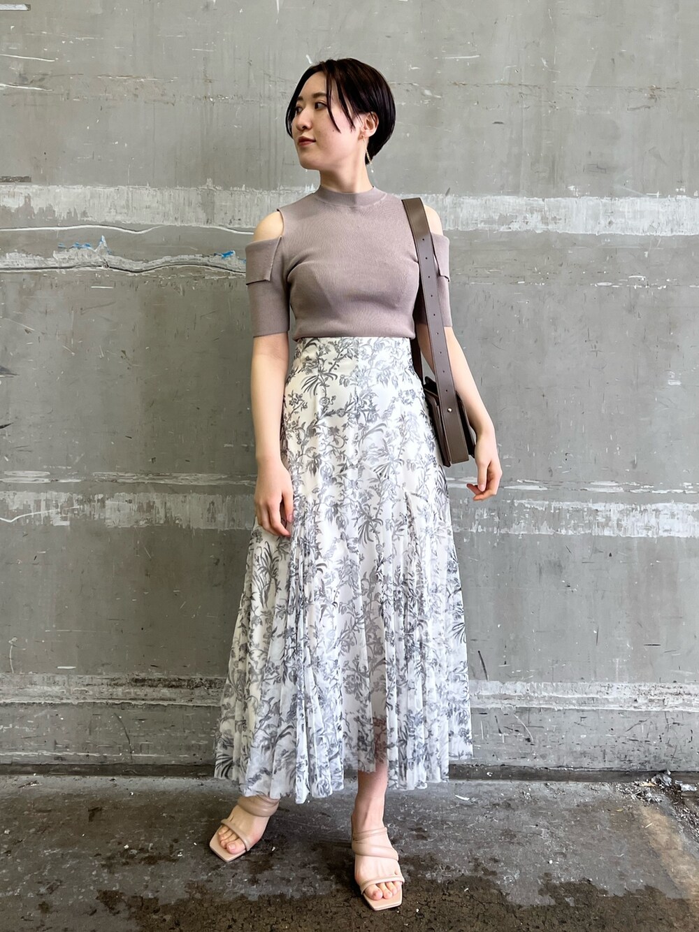 ベージュ系のノーカラーコート、ホワイト系のスカート、ベージュ系のサンダルを着用したレディースの冬コーディネートの5枚目の写真