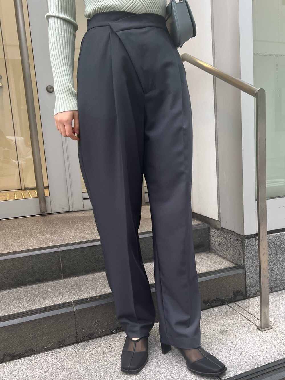 ブルー系のショルダーバッグ、グレー系のスラックス、グリーン系のニット/セーターを着用したレディースの冬コーディネートの7枚目の写真