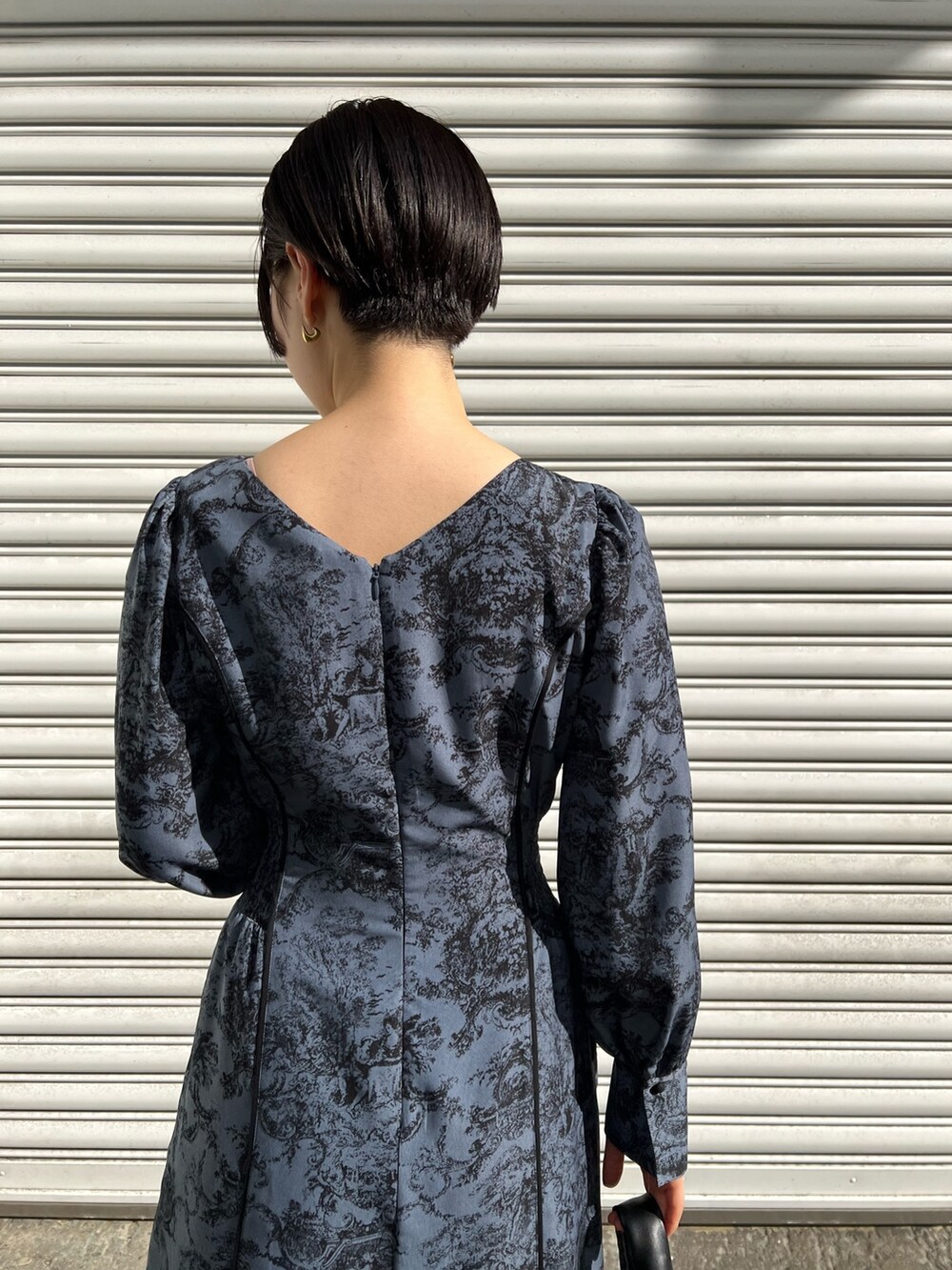 レッド系のブーツ、ブラック系のノーカラーコート、ブルー系のワンピースを着用したレディースの冬コーディネートの5枚目の写真