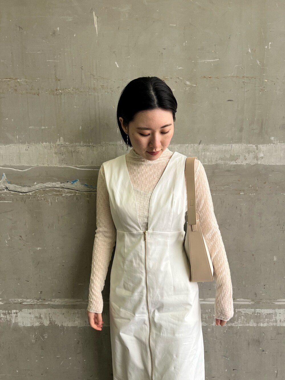 ホワイト系のジャンパースカート、ベージュ系のハンドバッグ、ホワイト系のTシャツ/カットソーを着用したレディースの春コーディネートの2枚目の写真