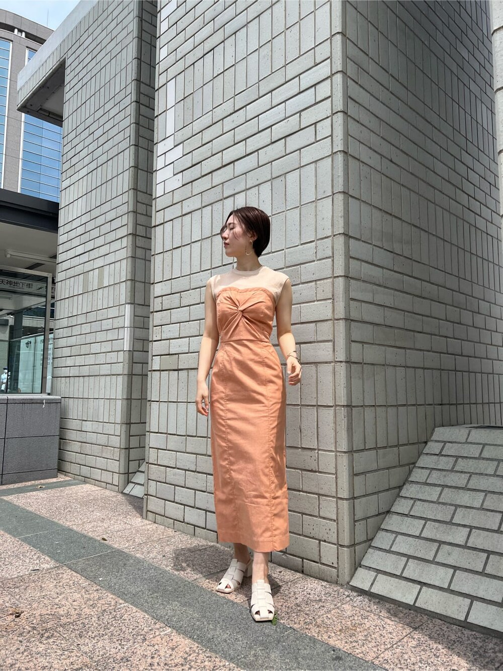 ホワイト系のブルゾン、オレンジ系のワンピース、ホワイト系のサンダルを着用したレディースの春コーディネートの2枚目の写真