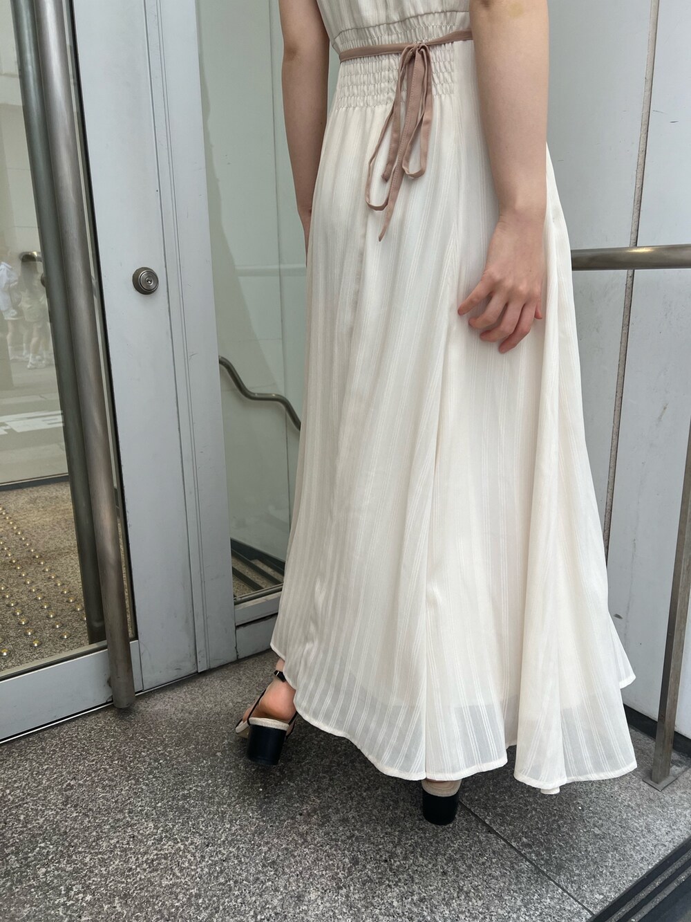 ブラック系のサンダル、ホワイト系のワンピースを着用したレディースの夏コーディネートの6枚目の写真