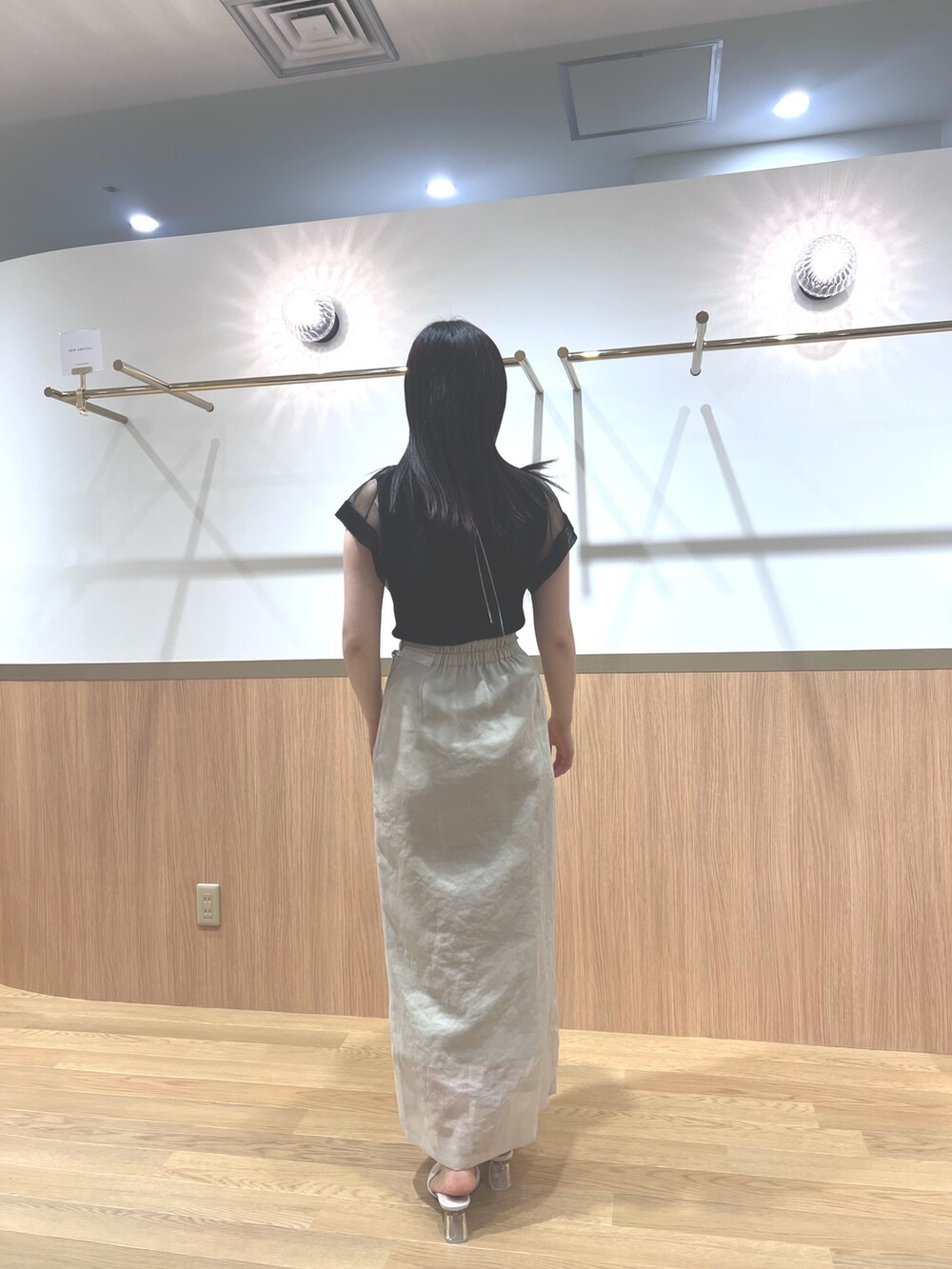 ブラック系のニット/セーター、ホワイト系のスカート、ホワイト系のサンダルを着用したレディースの春コーディネートの3枚目の写真