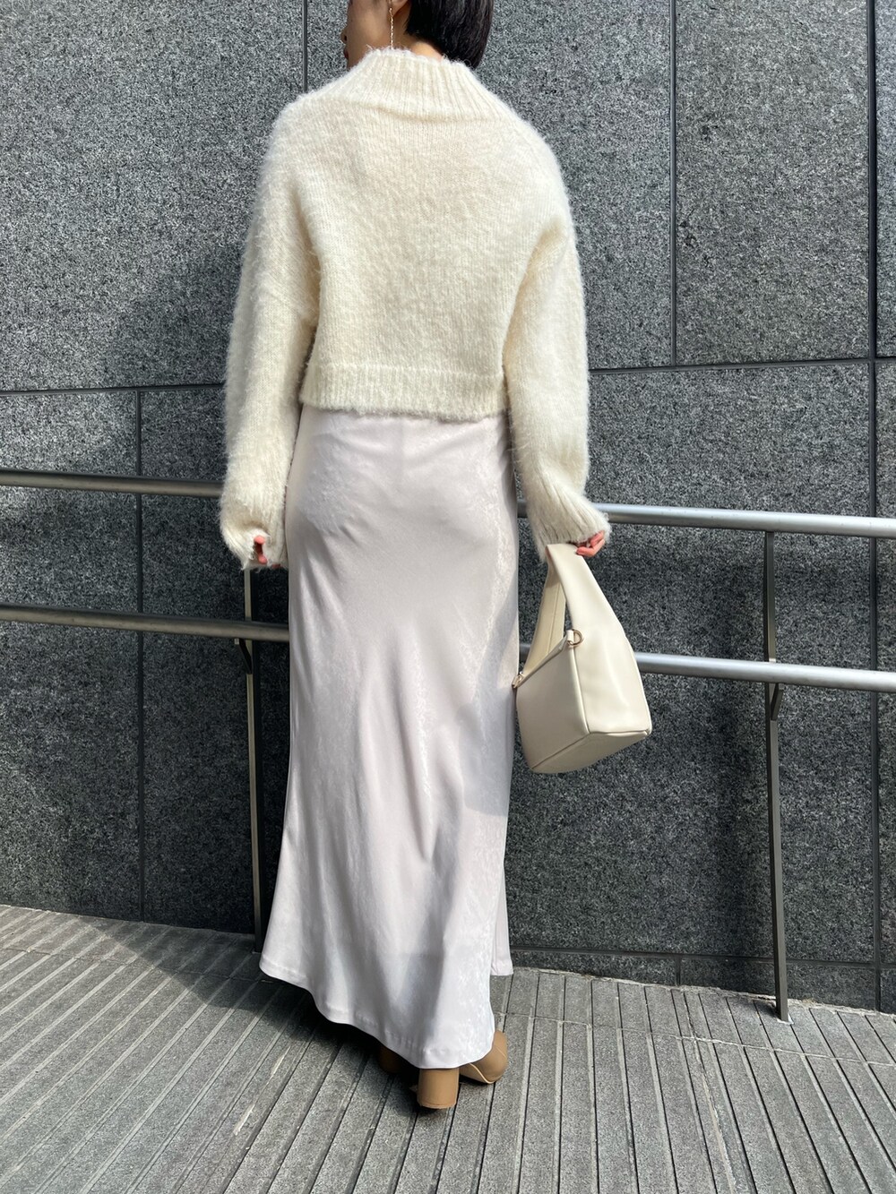 ホワイト系のスカート、ホワイト系のハンドバッグ、ピンク系のカーディガン/ボレロを着用したレディースの冬コーディネートの9枚目の写真