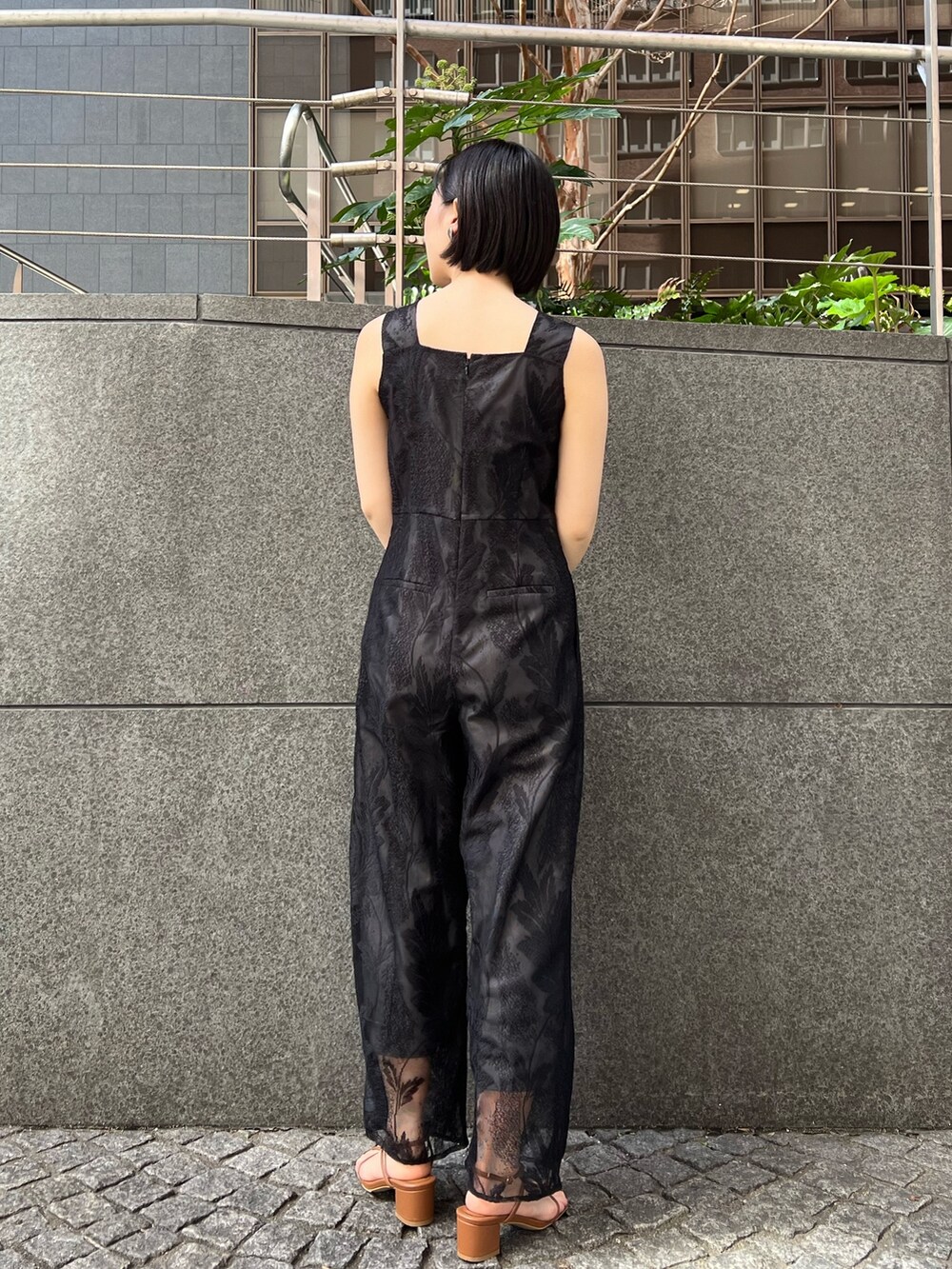 イエロー系のサンダル、ホワイト系のテーラードジャケット、ブラック系のつなぎ/オールインワンを着用したレディースの春コーディネートの6枚目の写真