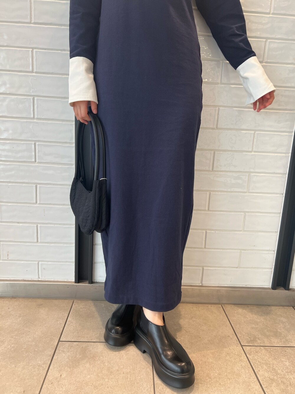 ブラック系のハンドバッグ、ブラック系のブーツ、ブルー系のワンピースを着用したレディースの秋コーディネートの6枚目の写真