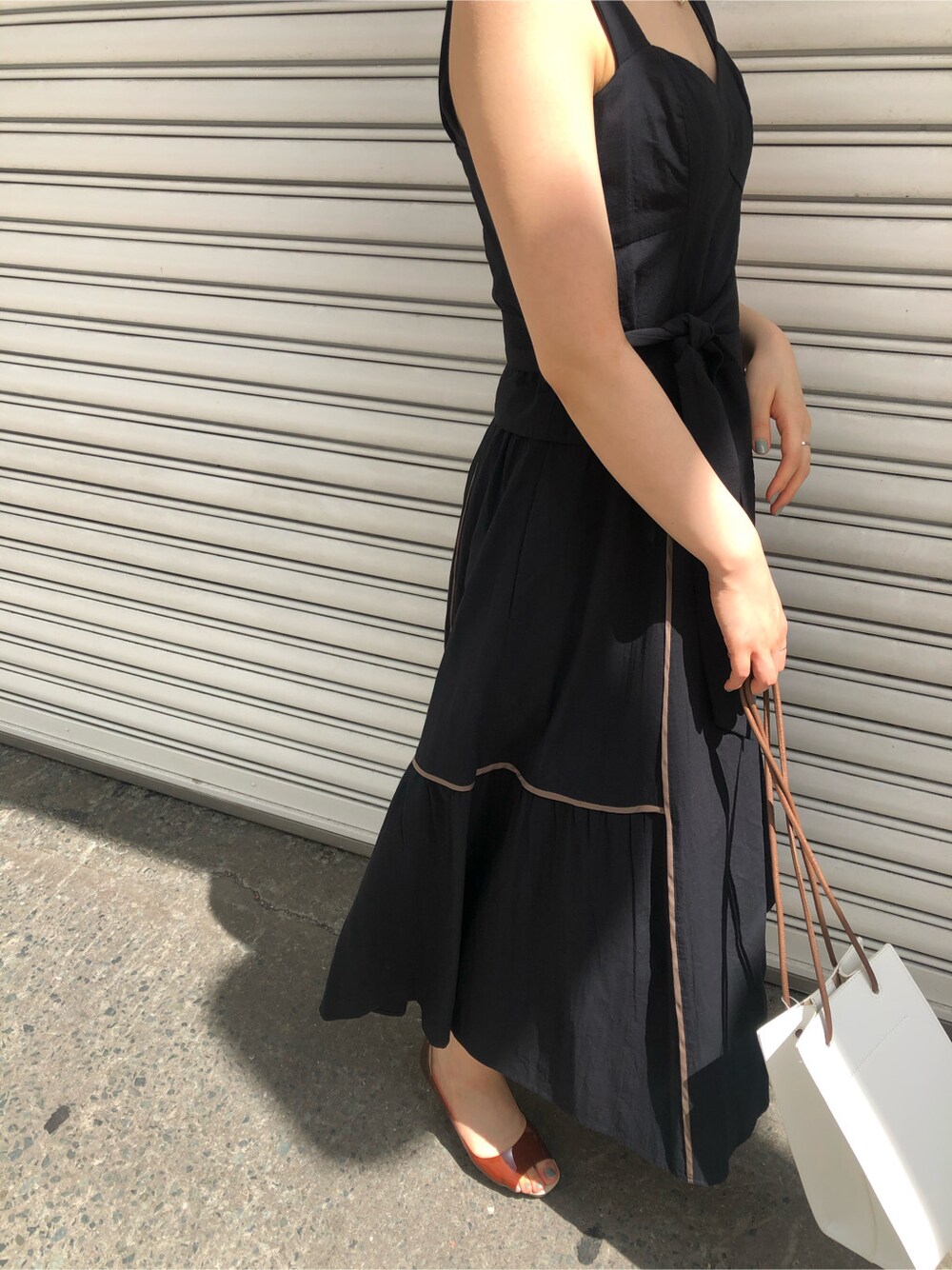 ブラウン系のパンプス、ホワイト系のハンドバッグ、ブラック系のワンピースを着用したレディースの春コーディネートの3枚目の写真