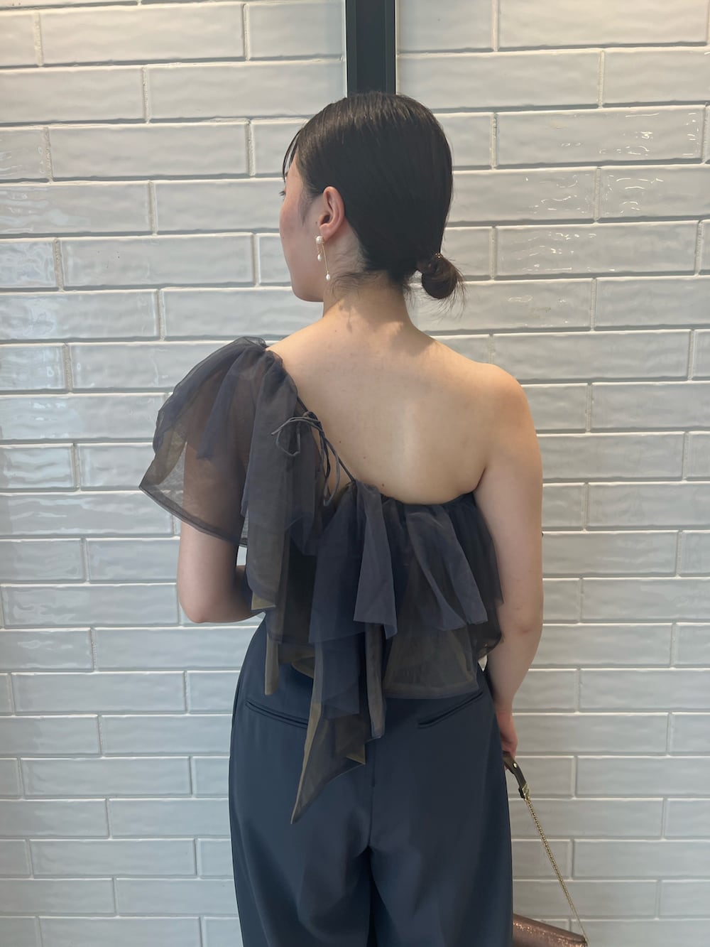 ゴールド系のハンドバッグ、ゴールド系のパンプス、グレー系のパンツドレスを着用したレディースの夏コーディネートの8枚目の写真