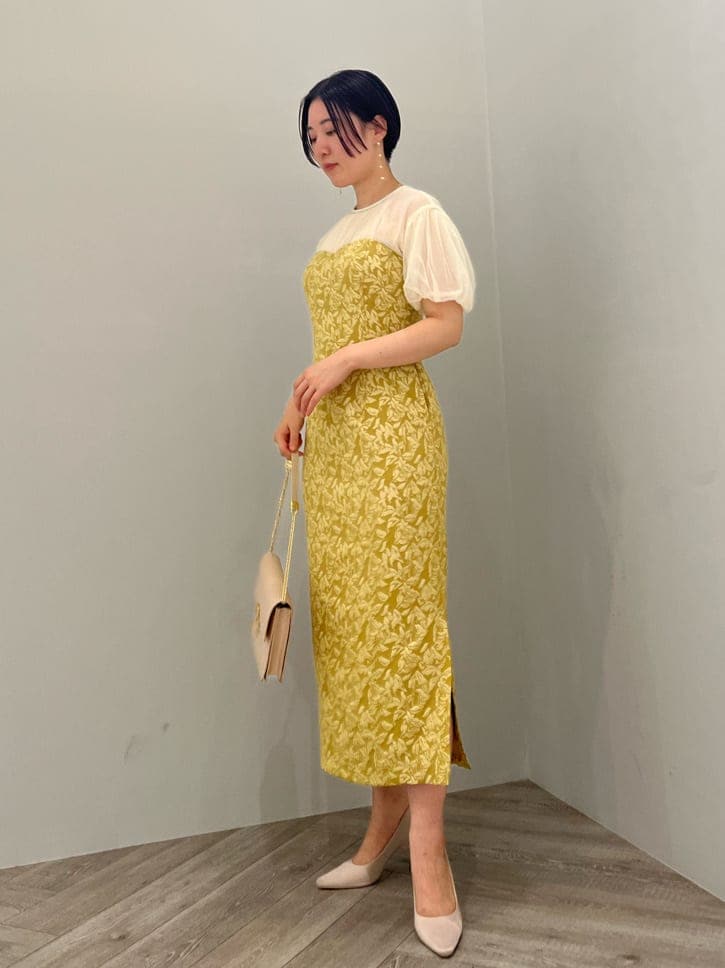 ベージュ系のパンプス、イエロー系のドレス、ベージュ系のクラッチバッグを着用したレディースの秋コーディネートの2枚目の写真