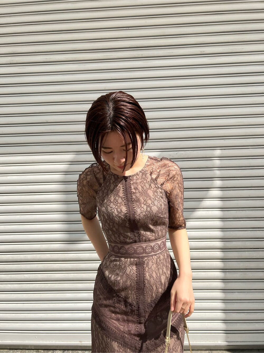 ホワイト系のノーカラーコート、ベージュ系のドレス、ベージュ系のクラッチバッグを着用したレディースの春コーディネートの6枚目の写真