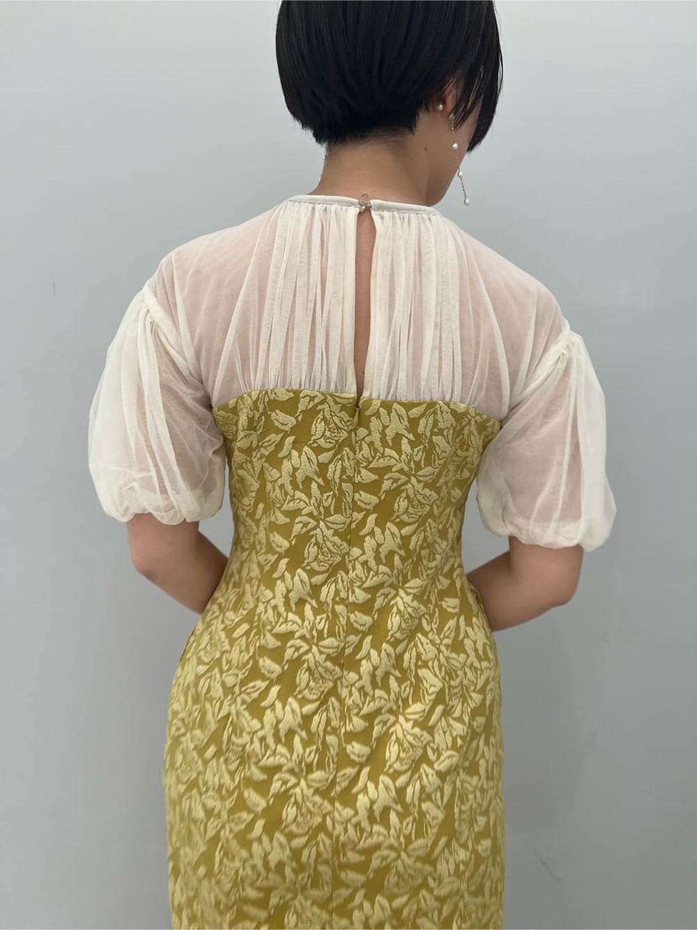 ベージュ系のパンプス、イエロー系のドレス、ベージュ系のクラッチバッグを着用したレディースの秋コーディネートの8枚目の写真