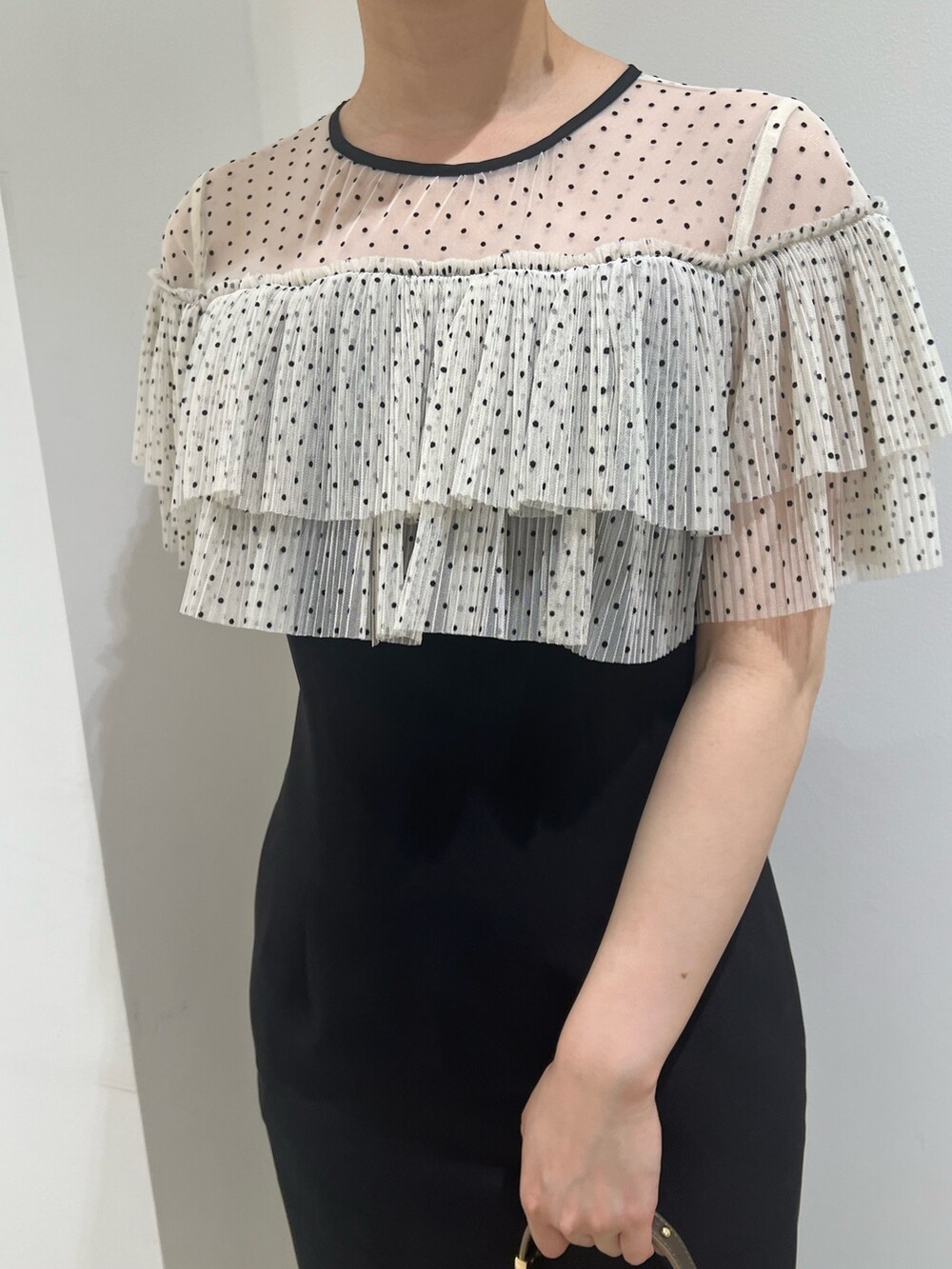 ゴールド系のパンプス、ゴールド系のハンドバッグ、ブラック系のドレスを着用したレディースの夏コーディネートの4枚目の写真