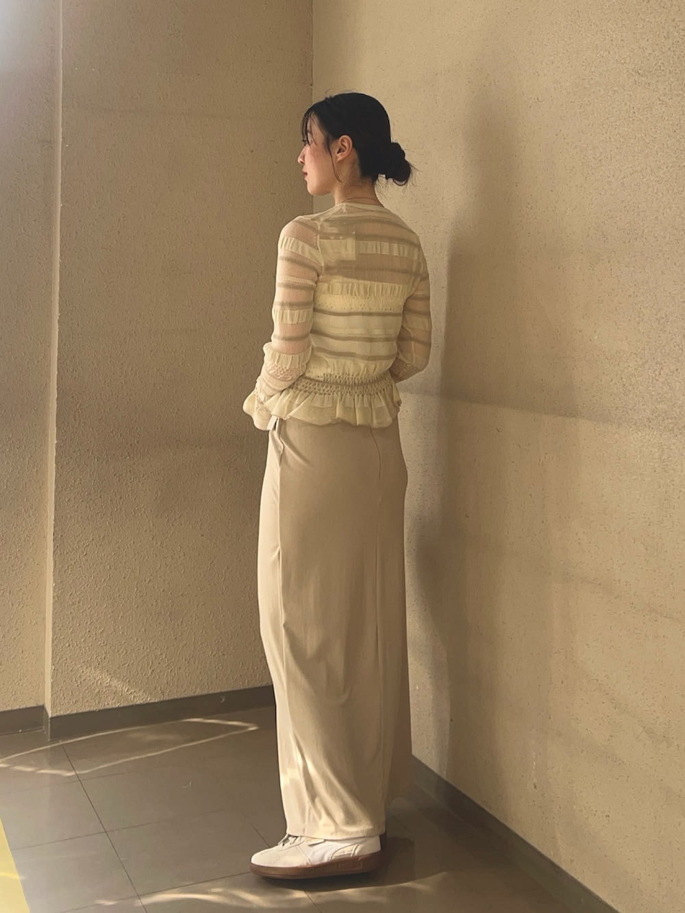 ベージュ系のスカート、ホワイト系のニット/セーター、ホワイト系のスニーカーを着用したレディースの春コーディネートの2枚目の写真