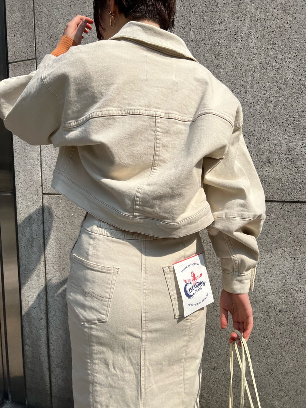 ホワイト系のブルゾン、ホワイト系のスカート、ホワイト系のハンドバッグを着用したレディースの春コーディネートの9枚目の写真