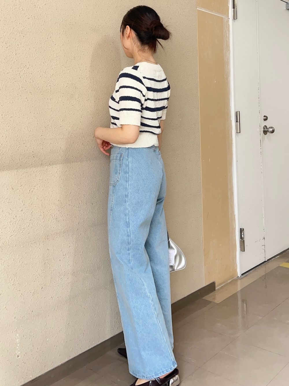 ブルー系のデニムパンツ、ホワイト系のニット/セーター、ブラック系のパンプスを着用したレディースの春コーディネートの2枚目の写真