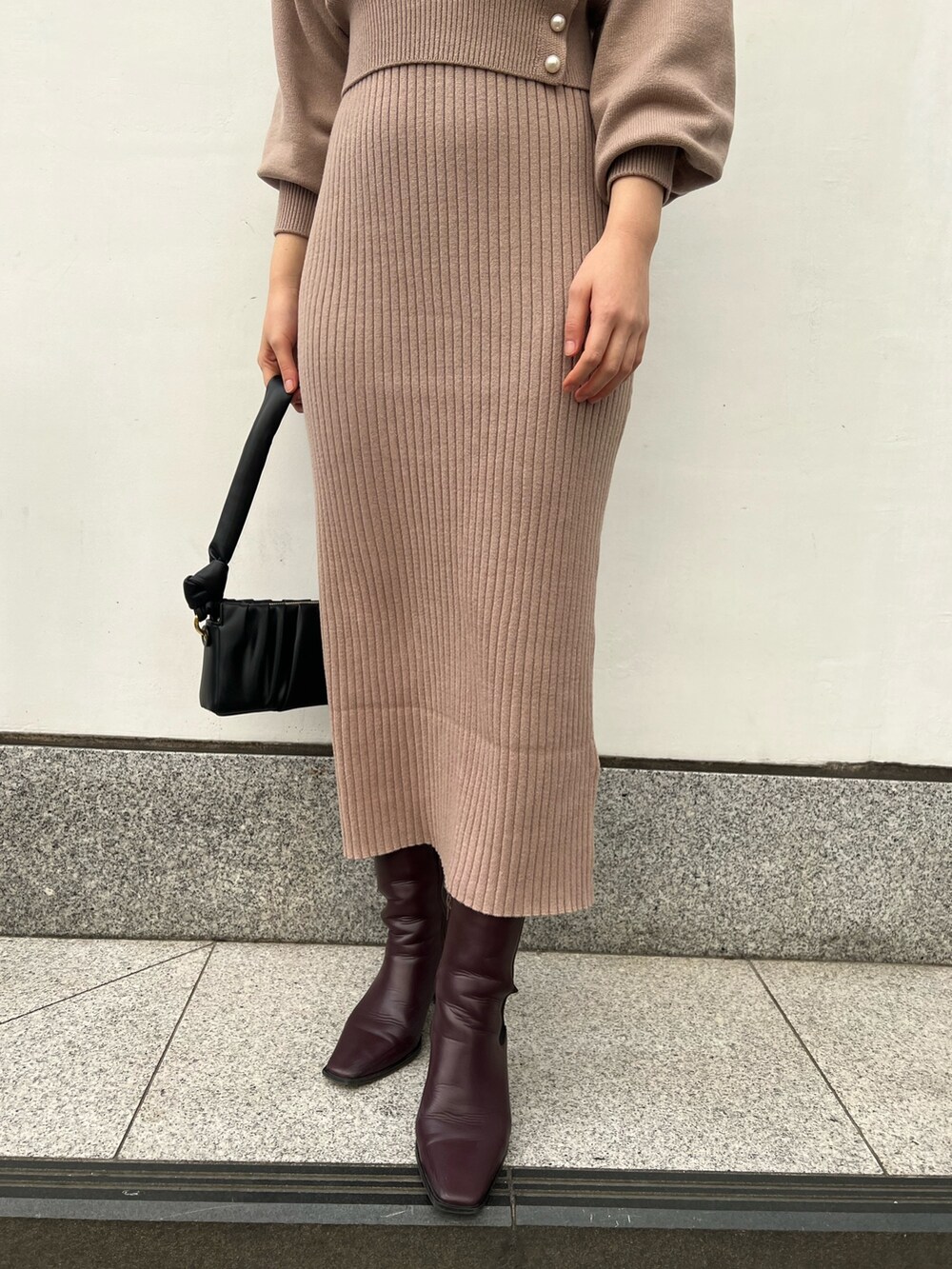 レッド系のブーツ、ブラック系のハンドバッグ、ベージュ系のワンピースを着用したレディースの冬コーディネートの9枚目の写真