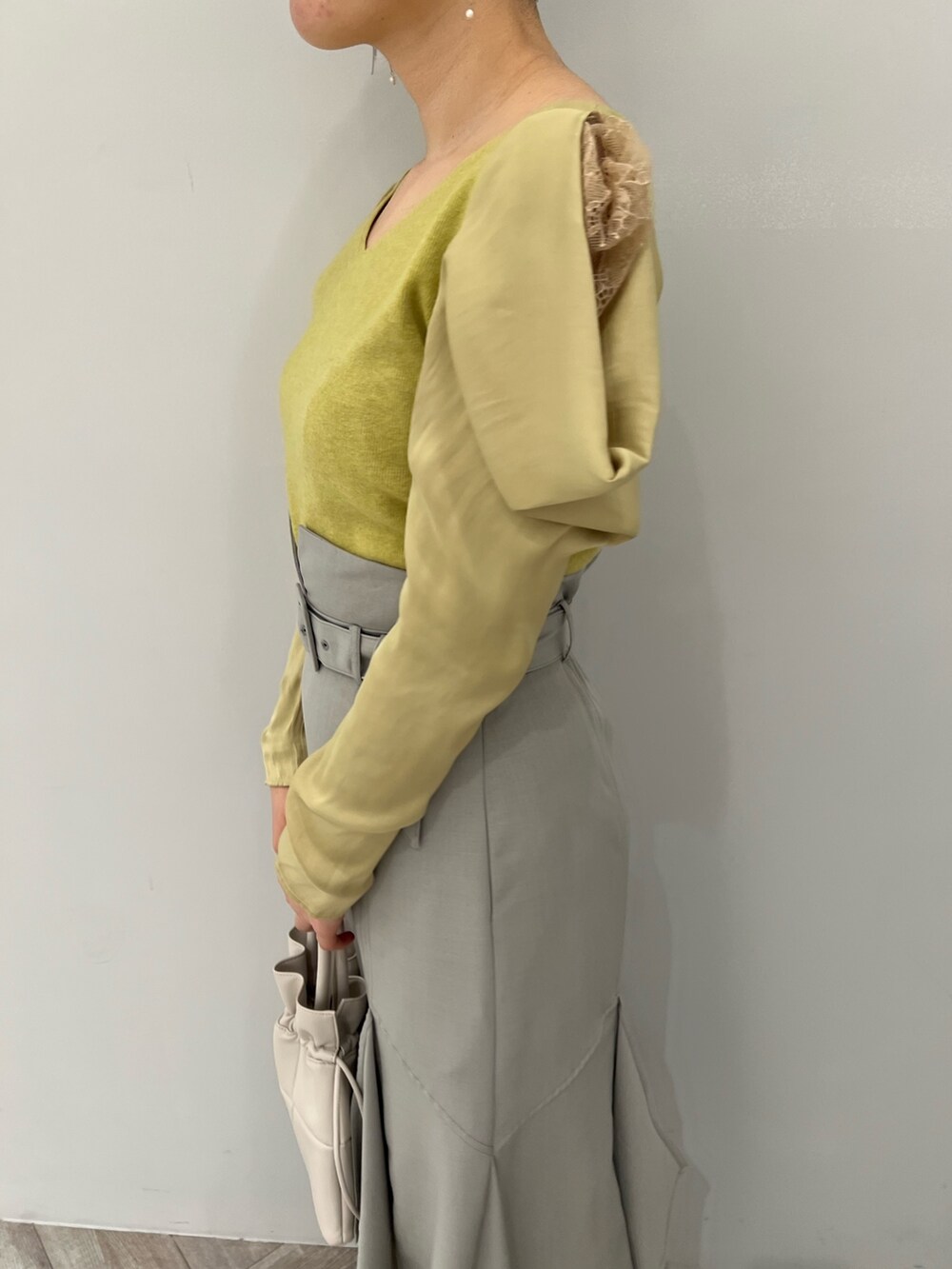 ブラック系のブーツ、ホワイト系のハンドバッグ、グリーン系のスカートを着用したレディースの冬コーディネートの5枚目の写真