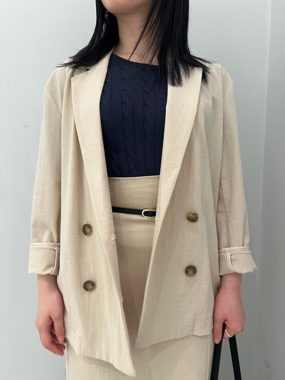 ブルー系のニット/セーター、ホワイト系のサンダル、ベージュ系のテーラードジャケットを着用したレディースの春コーディネートの4枚目の写真