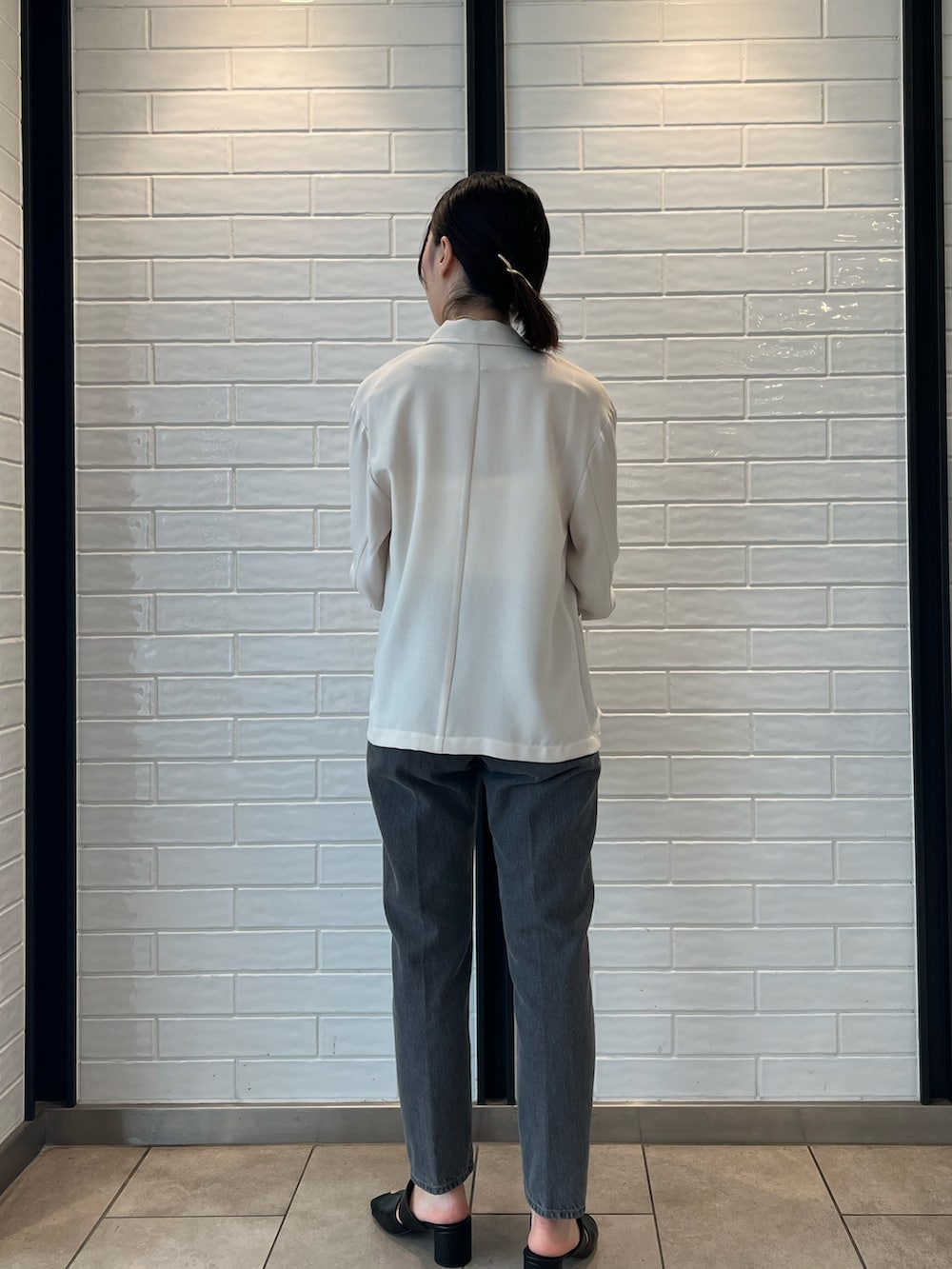 ホワイト系のキャミソール、ブラック系のデニムパンツ、ベージュ系のテーラードジャケットを着用したレディースの夏コーディネートの2枚目の写真