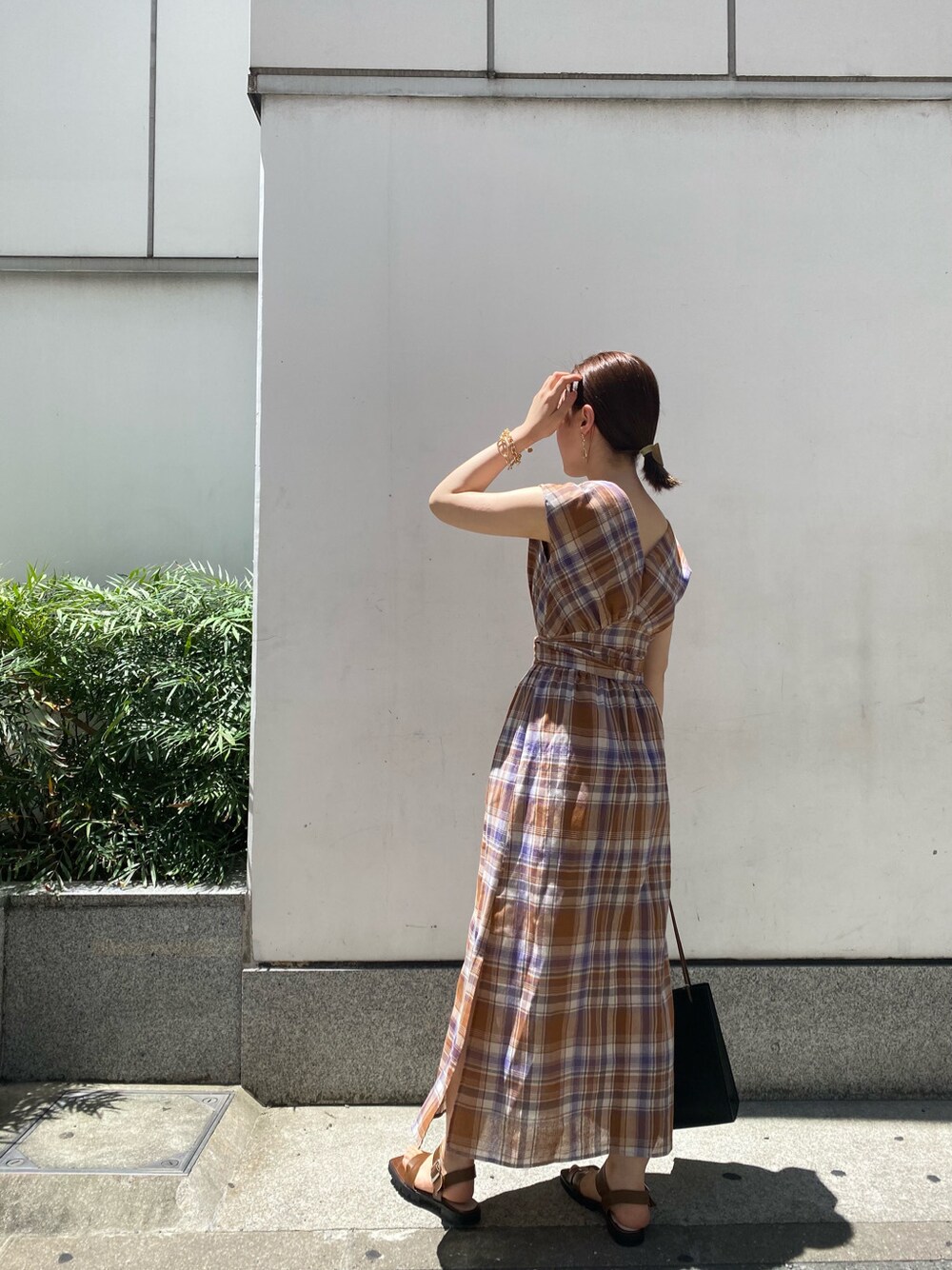 ブラック系のハンドバッグ、ブラウン系のサンダル、ブラウン系のワンピースを着用したレディースの夏コーディネートの3枚目の写真