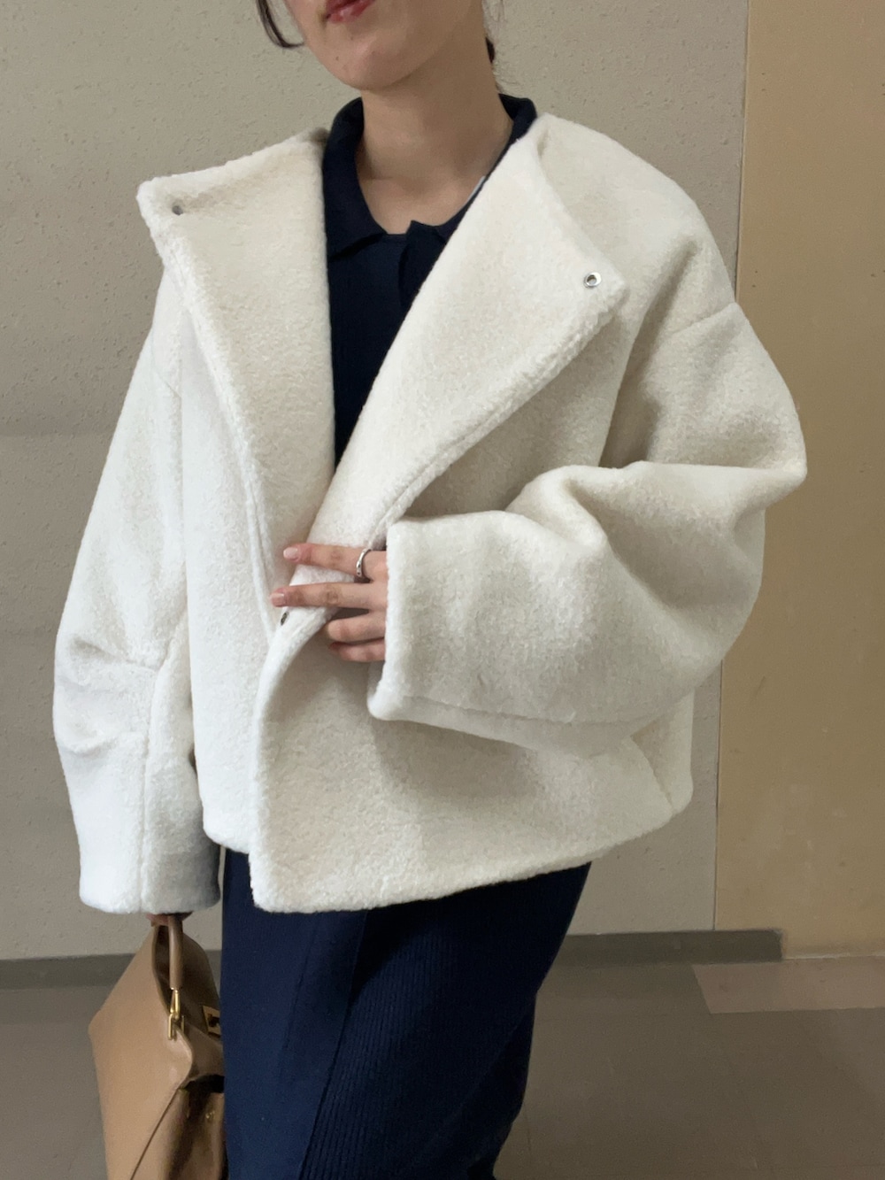 ホワイト系のブルゾン、ブルー系のワンピース、ブラック系のブーツを着用したレディースの秋コーディネートの4枚目の写真