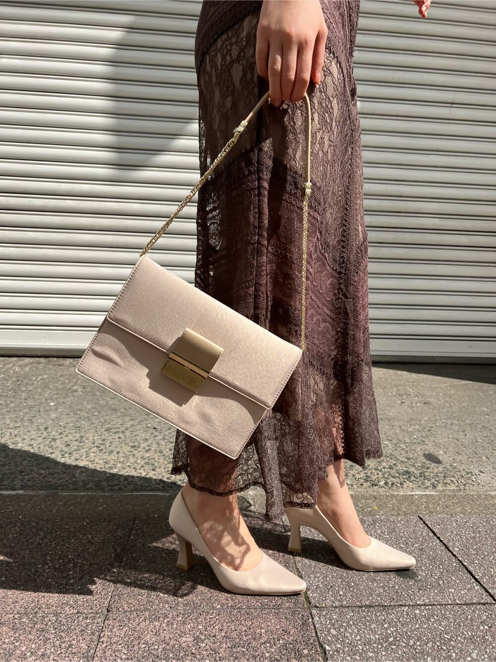 ホワイト系のノーカラーコート、ベージュ系のドレス、ベージュ系のクラッチバッグを着用したレディースの春コーディネートの4枚目の写真