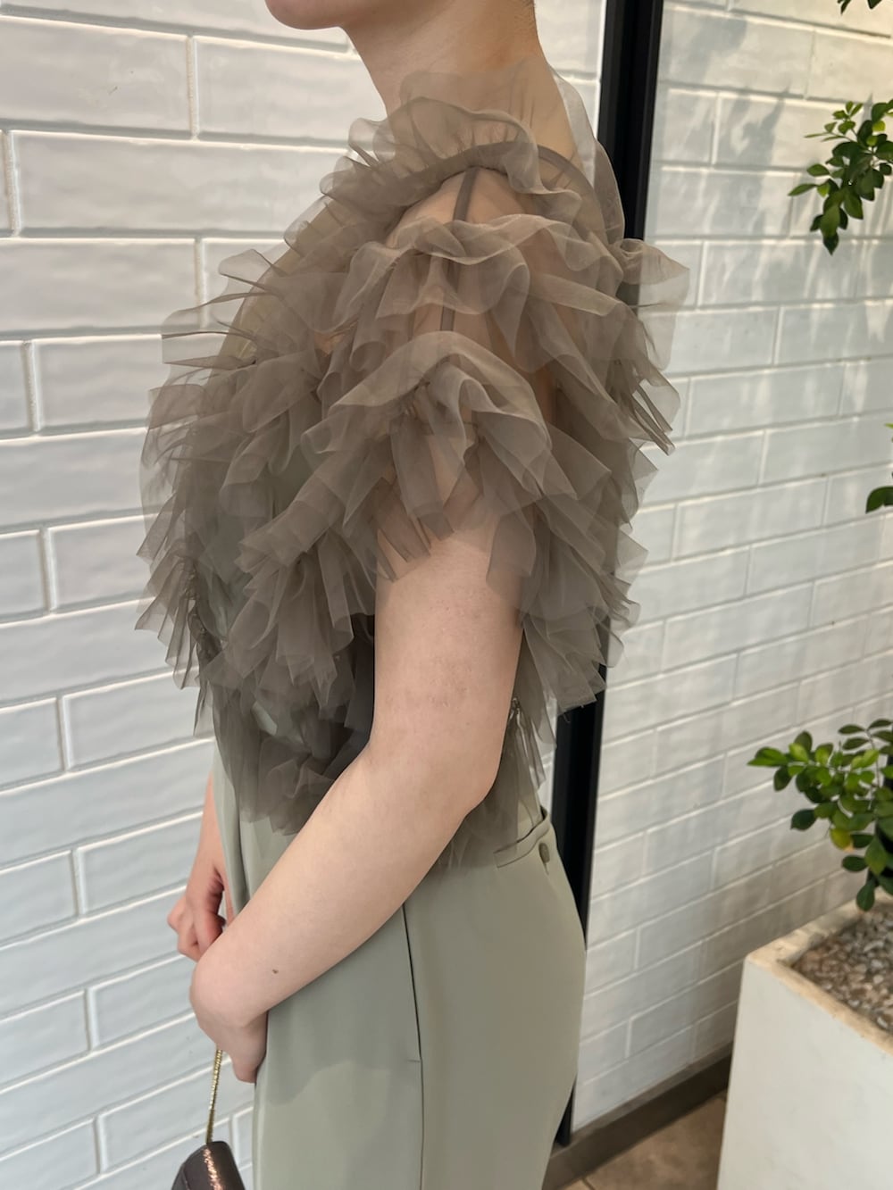 シルバー系のパンプス、シルバー系のハンドバッグ、グリーン系のパンツドレスを着用したレディースの春コーディネートの8枚目の写真