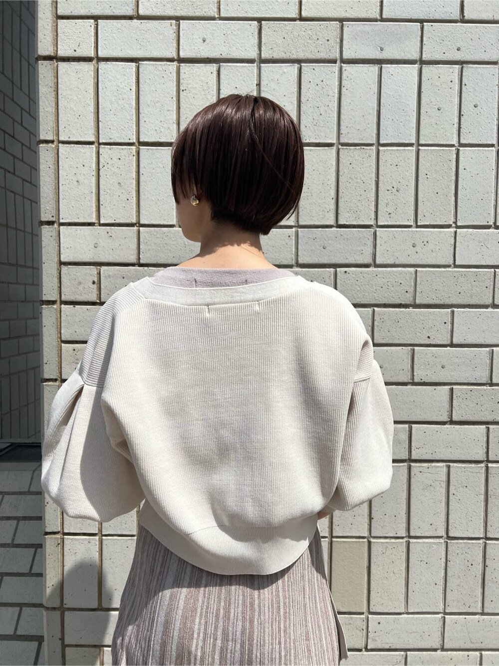 ベージュ系のワンピース、ホワイト系のカーディガン/ボレロ、ゴールド系のバングル/リストバンドを着用したレディースの春コーディネートの6枚目の写真