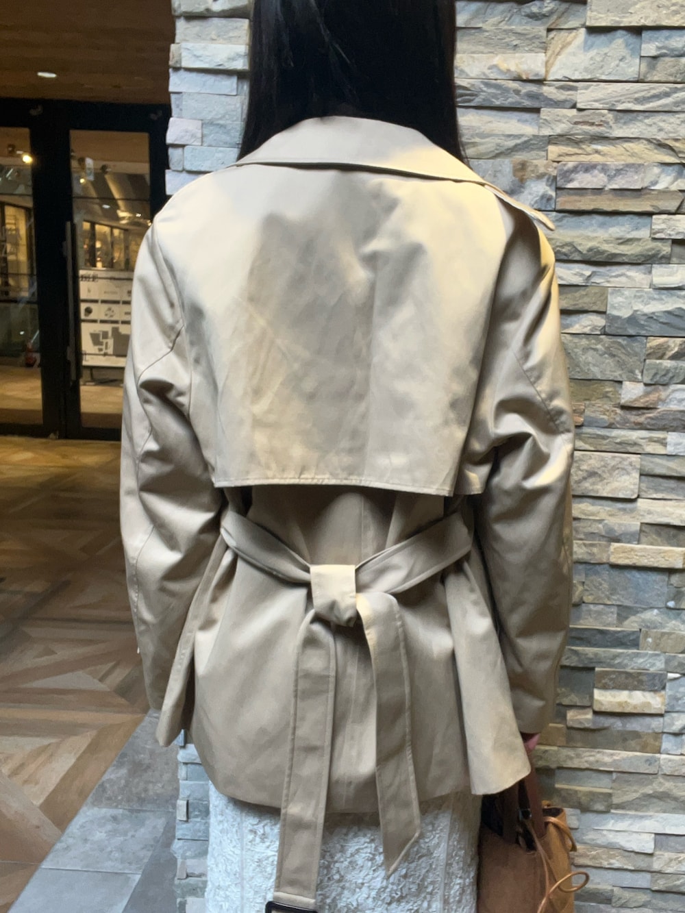 ブラウン系のハンドバッグ、ホワイト系のワンピース、ベージュ系のトレンチコートを着用したレディースの冬コーディネートの5枚目の写真