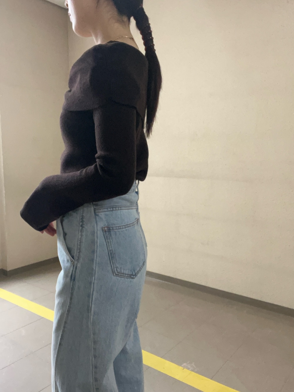 ブルー系のデニムパンツ、ブラウン系のニット/セーター、イエロー系のハンドバッグを着用したレディースの冬コーディネートの5枚目の写真