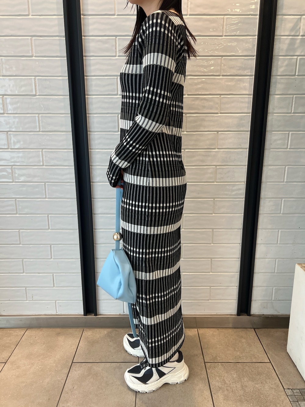 ブルー系のショルダーバッグ、ブラック系のワンピース、グレー系のスニーカーを着用したレディースの冬コーディネートの7枚目の写真