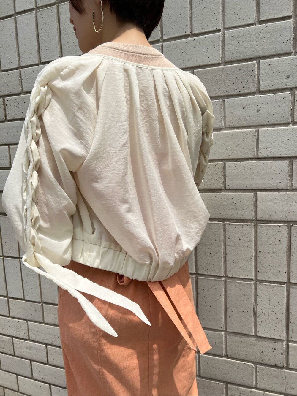 ホワイト系のブルゾン、オレンジ系のワンピース、ホワイト系のサンダルを着用したレディースの春コーディネートの10枚目の写真