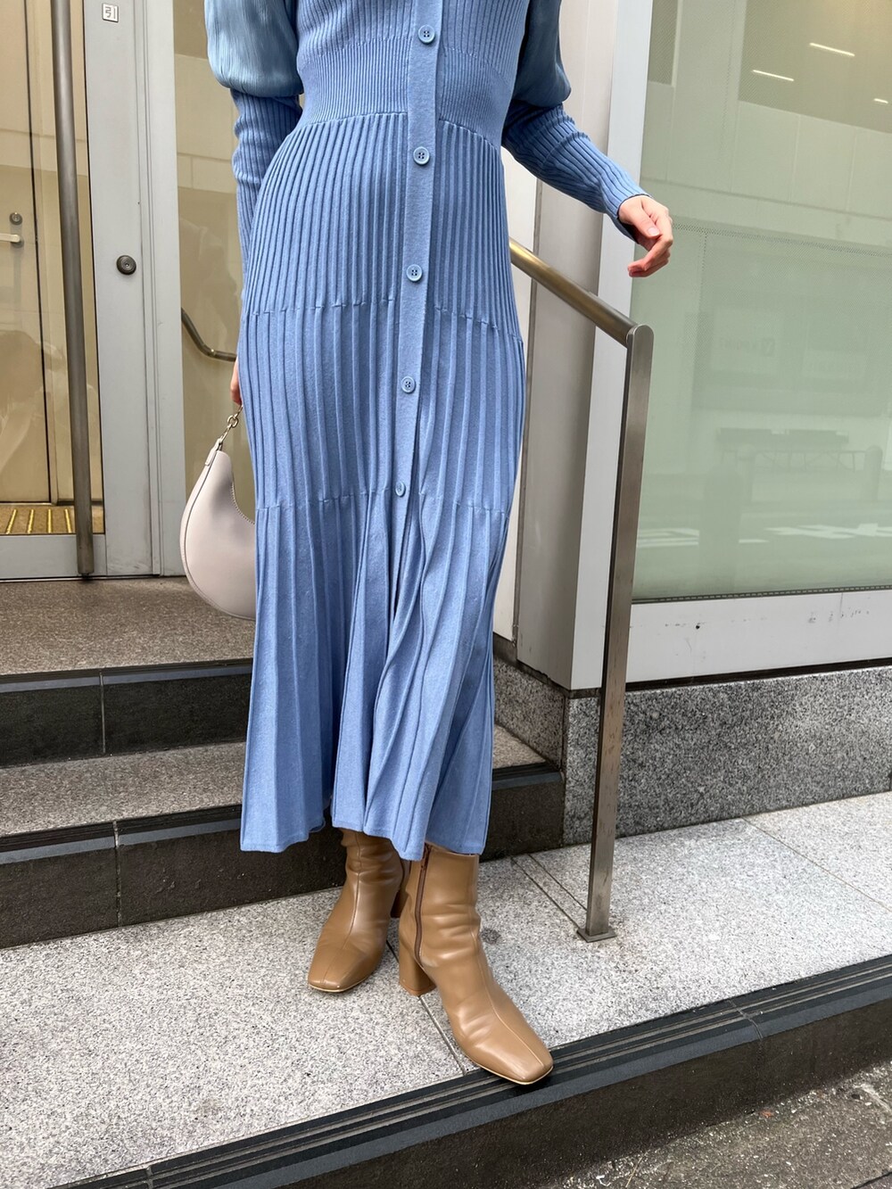 ベージュ系のブーツ、ホワイト系のハンドバッグ、ホワイト系のノーカラーコートを着用したレディースの冬コーディネートの9枚目の写真