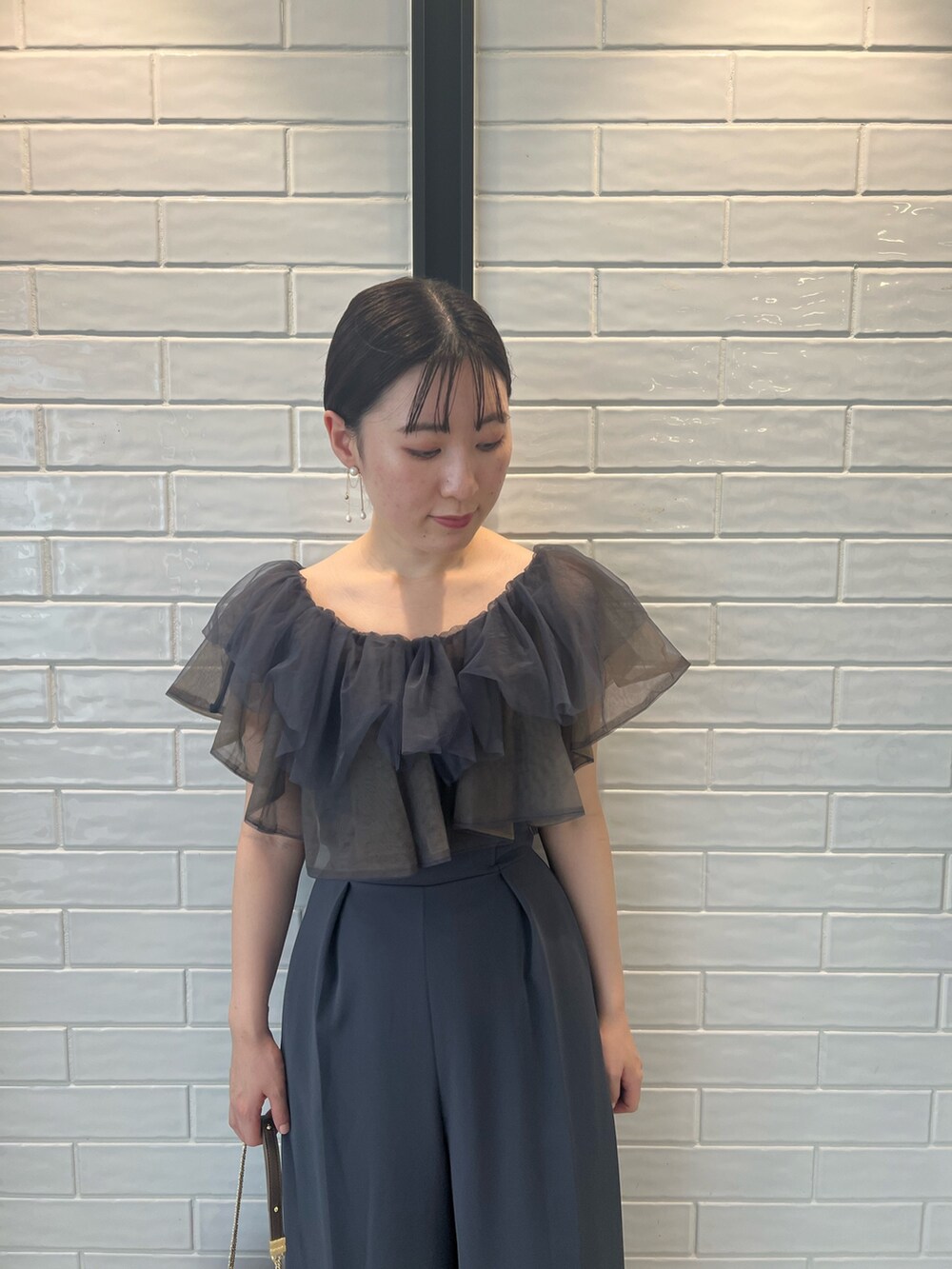 ゴールド系のハンドバッグ、ゴールド系のパンプス、グレー系のパンツドレスを着用したレディースの夏コーディネートの4枚目の写真