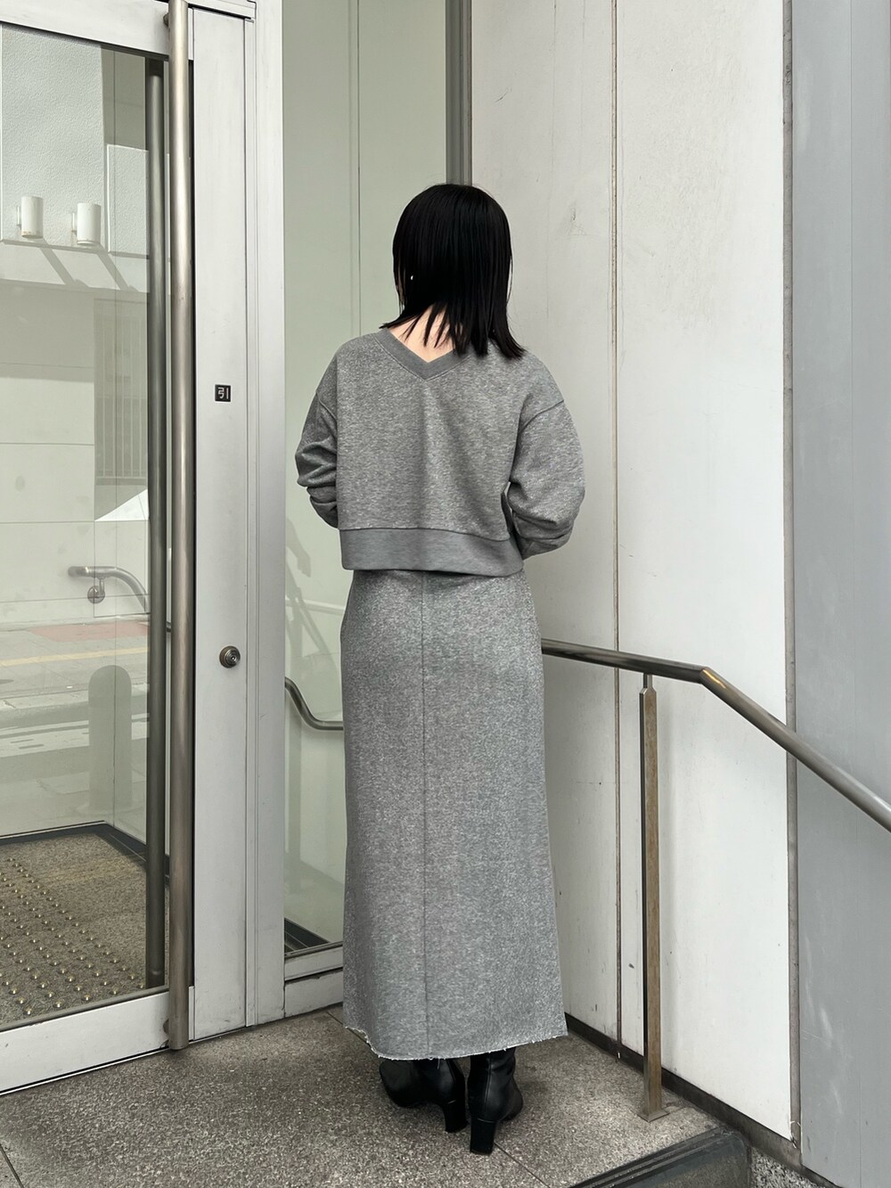 ブラック系のブーツ、グレー系のスカート、グレー系のスウェットを着用したレディースの秋コーディネートの3枚目の写真