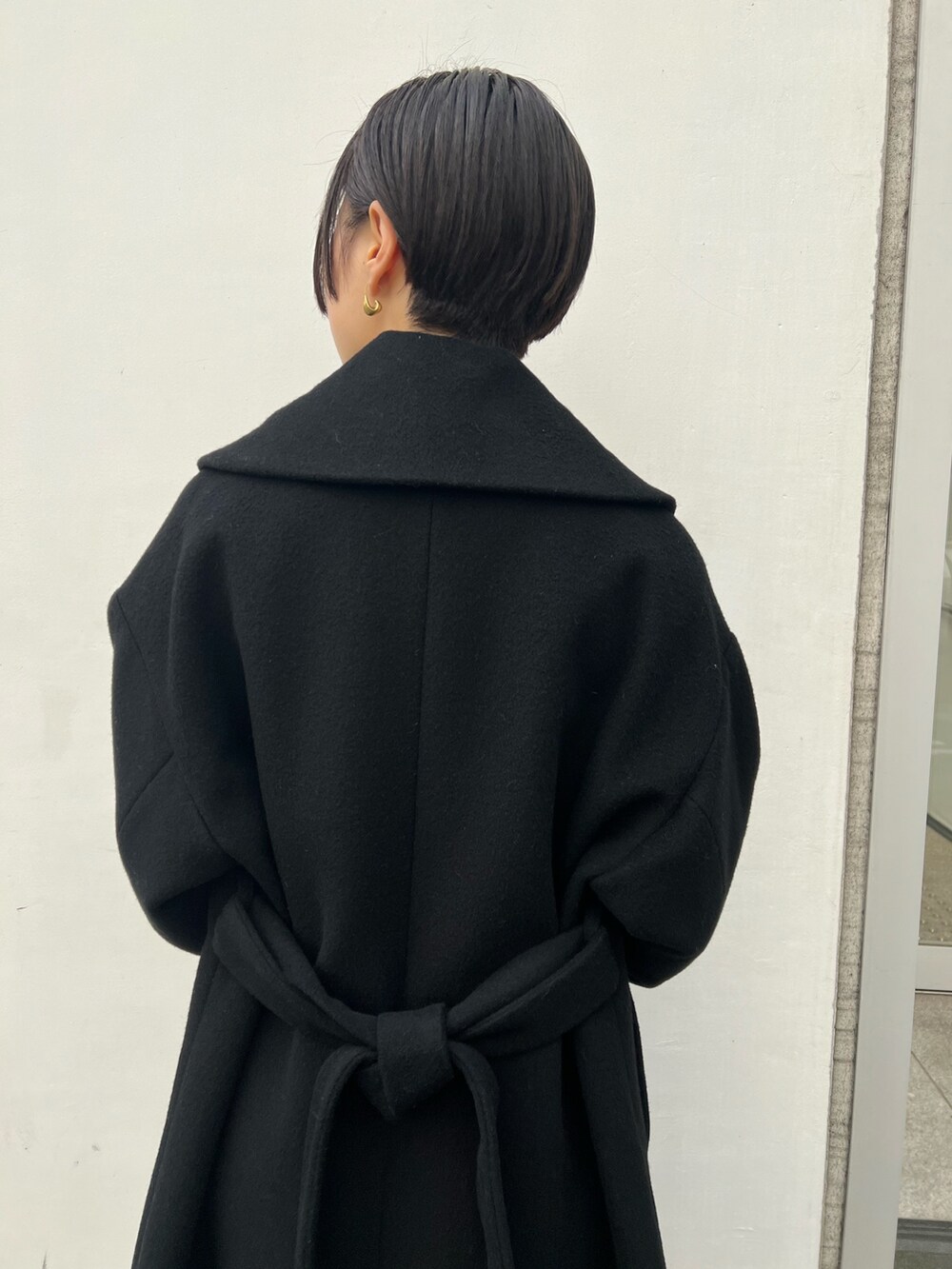 レッド系のブーツ、ブラック系のハンドバッグ、ベージュ系のワンピースを着用したレディースの冬コーディネートの4枚目の写真