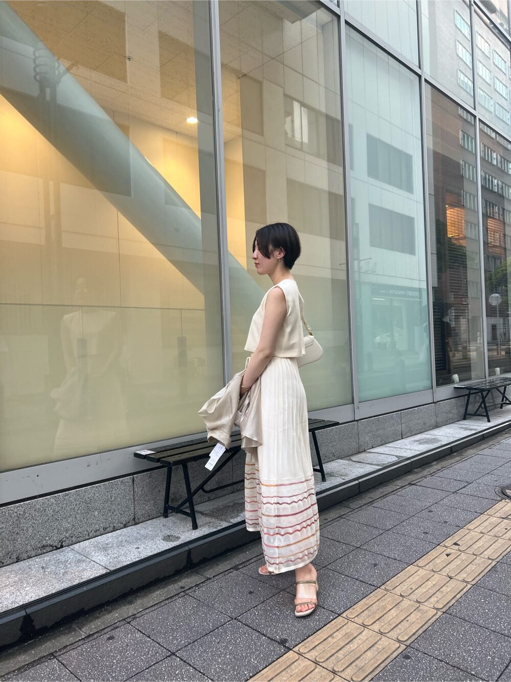 ホワイト系のワンピース、ホワイト系のショルダーバッグ、ゴールド系のピアス（両耳用）を着用したレディースの夏コーディネートの3枚目の写真