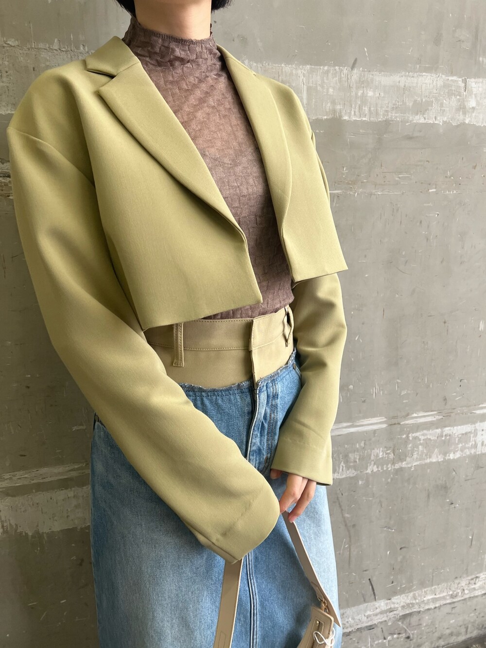 シルバー系のパンプス、グリーン系のテーラードジャケット、グリーン系のデニムスカートを着用したレディースの冬コーディネートの4枚目の写真