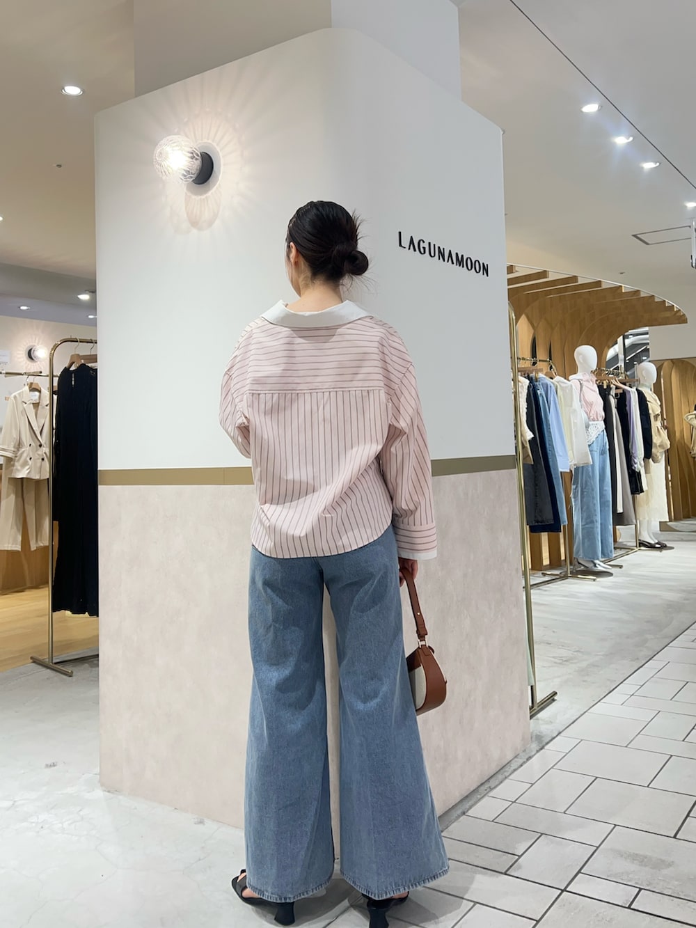 ピンク系のシャツ/ブラウス、ブルー系のデニムパンツ、ブラウン系のハンドバッグを着用したレディースの春コーディネートの3枚目の写真