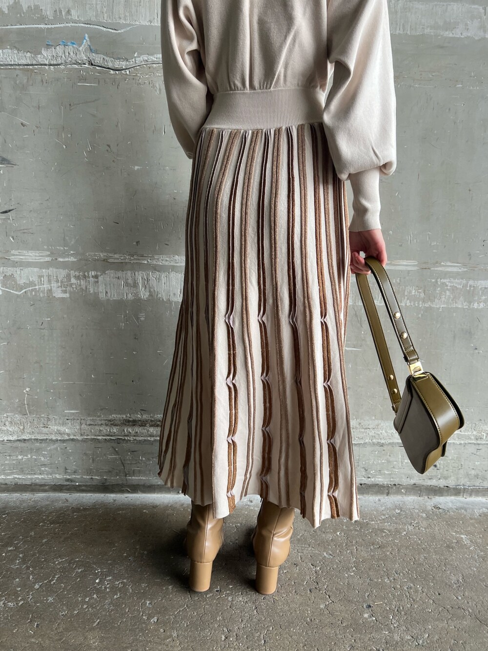 ブラウン系のショルダーバッグ、ベージュ系のブーツ、グレー系のその他アウターを着用したレディースの冬コーディネートの10枚目の写真