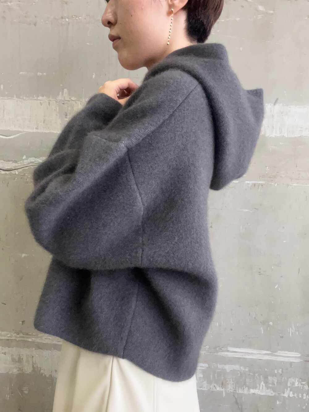 ベージュ系のブーツ、グレー系のパーカー、ホワイト系のスカートを着用したレディースの秋コーディネートの5枚目の写真