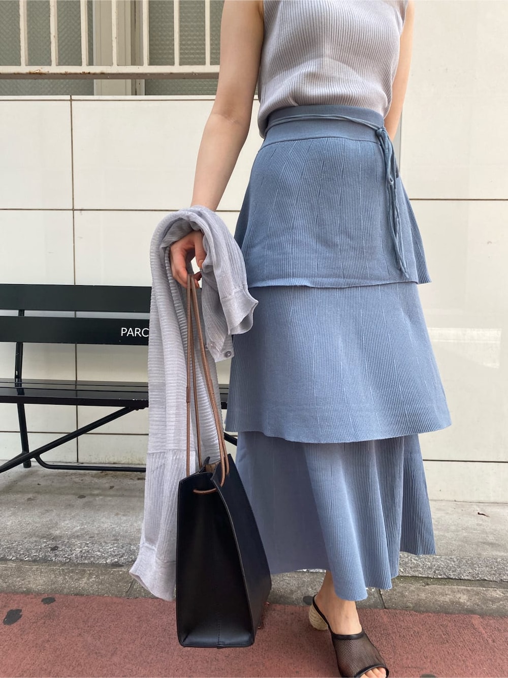 ブラック系のハンドバッグ、ブルー系のスカート、グレー系のニット/セーターを着用したレディースの夏コーディネートの5枚目の写真