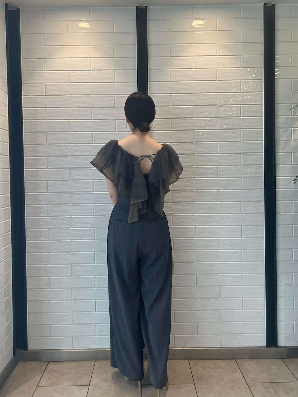 ゴールド系のハンドバッグ、ゴールド系のパンプス、グレー系のパンツドレスを着用したレディースの夏コーディネートの3枚目の写真