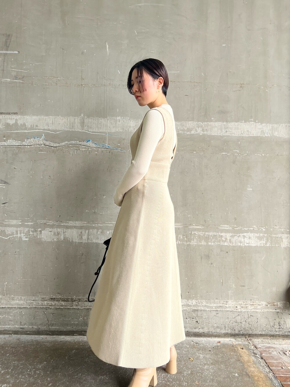 ベージュ系のブーツ、ブラック系のハンドバッグ、ホワイト系のニット/セーターを着用したレディースの秋コーディネートの4枚目の写真