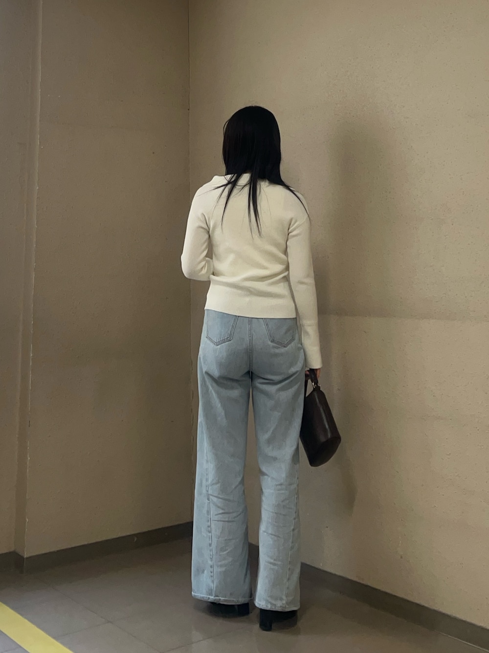 ホワイト系のアンサンブル、ブルー系のデニムパンツを着用したレディースの冬コーディネートの3枚目の写真