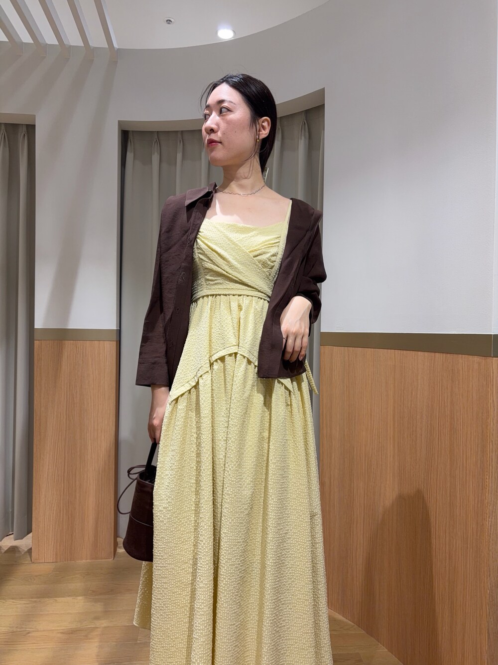 イエロー系のワンピース、ブラウン系のシャツ/ブラウス、ベージュ系のサンダルを着用したレディースの夏コーディネートの3枚目の写真