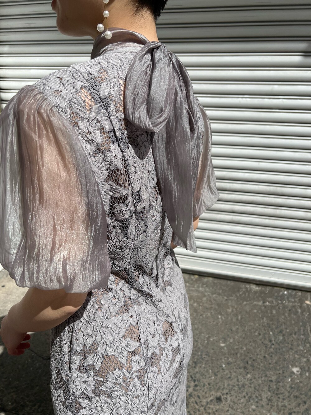 ブルー系のノーカラーコート、シルバー系のパンプス、シルバー系のクラッチバッグを着用したレディースの春コーディネートの9枚目の写真