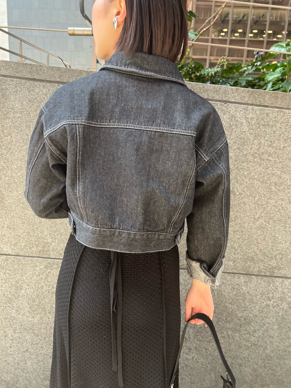 ブラック系のデニムジャケット、ホワイト系のパンプス、ブラック系のハンドバッグを着用したレディースの春コーディネートの3枚目の写真